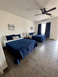 Un dormitorio con dos camas y un ventilador de techo. en Costa del Sol Hotel & Sportfishing, en Bahía de los Ángeles