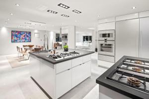 cocina con armarios blancos y encimera negra en Hollywood Hills Luxury Modern Home with Pool & Sunset views en Los Ángeles