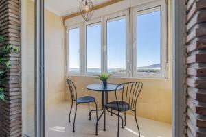ein kleiner Tisch und Stühle in einem Zimmer mit Fenstern in der Unterkunft Suite Homes Hesperides 914 in Málaga