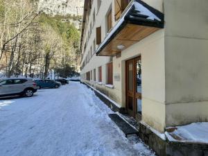a snow covered sidewalk next to a building with a door at Moncayo Canfranc in Canfranc-Estación