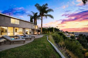 a house with couches and palm trees at sunset at Hollywood Hills Luxury Modern Home with Pool & Sunset views in Los Angeles