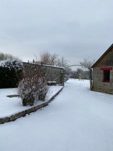 a yard covered in snow next to a building at Maison "La Butte" - Suisse Normande in Ségrie-Fontaine