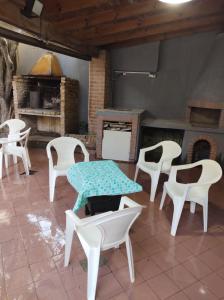 Habitación con sillas blancas, mesa y chimenea. en Dakini Hostel en Lomas de Zamora