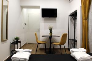 a room with two beds and a table and chairs at BlackWoody Contemporary Rooms - Napoli Centro Storico in Naples