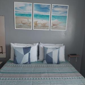 una camera con un letto con tre immagini appese al muro di Amor e aconchego a Praia Grande