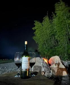 a bottle of wine and two glasses next to a fire at wellgaya ecovillas in Villa Flor