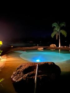 a swimming pool at night with a palm tree at wellgaya ecovillas in Villa Flor