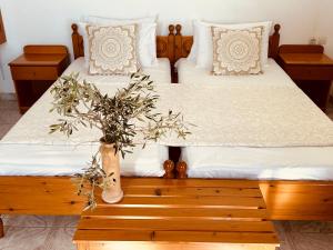 two beds with white sheets and a plant on a wooden table at Studios Fokia Beach in Amoopi