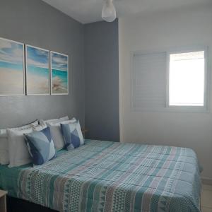 una camera da letto con un letto con cuscini blu e bianchi di Amor e aconchego a Praia Grande