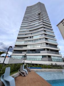 a tall building with a pool in front of it at Fiusa Dream 153 in Ribeirão Preto