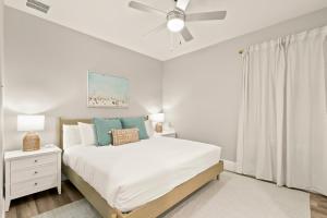a white bedroom with a bed and a ceiling fan at NEW! Canopy Cabana - Luxury Downtown Apartment in Safety Harbor