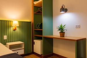 a bedroom with green walls and a desk with a plant at Pousada Valhacouto in Paraty +39 photos