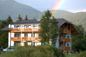 a large building with a rainbow in the background at B&B Hotel Heidi in Dobbiaco