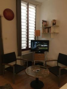 uma sala de estar com uma televisão e uma mesa de centro em Appart sympa dans le vieux Nimes em Nîmes