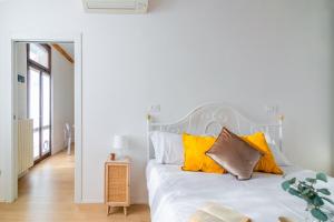 una camera da letto con un letto bianco con cuscini gialli di La Corte 48 - Pavia City - by Host4U a Pavia