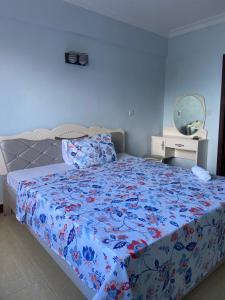 a bedroom with a bed with a floral bedspread and a mirror at Ocean view Home stay in Dar es Salaam