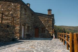 ein Steingebäude mit einer Veranda und einem Holzzaun in der Unterkunft Casas do Oiteirinho in Arganil