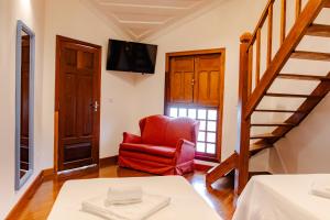 a living room with a red chair and a staircase at Pousada Valhacouto in Paraty