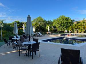 a restaurant with tables and umbrellas next to a pool at Condominio reserva imbassai in Mata de Sao Joao