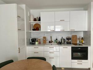 uma cozinha com armários brancos e uma mesa de madeira em Cozy Apartment Near the Train Station em Rueil-Malmaison