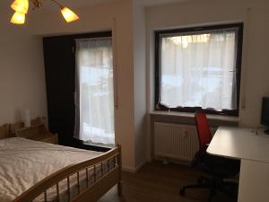 a bedroom with a bed and a desk and two windows at Apartment Henri in Schönwald +25 photos