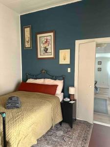 1 dormitorio con cama y pared azul en Wensel Cottage in downtown Natchez en Natchez