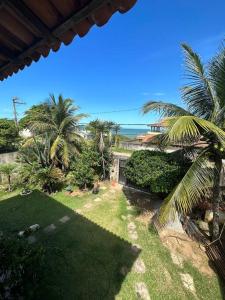 uma vista para um quintal com palmeiras e o oceano em Casa em frente a praia em Vila Velha