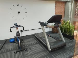 una bicicletta e un tapis roulant accanto a un muro con un orologio di Orange Suites by Vibra Bonita a Medellín