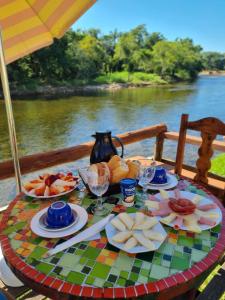 a table with plates of food on a table near the water at Pousada Siroba Beira Rio in Morretes