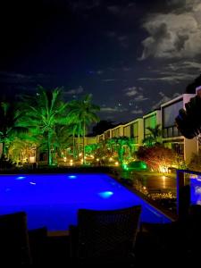 a swimming pool at night with palm trees and buildings at EXCLUSIVE RESIDENCE, BARRA GRANDE, PENINSULA DE MARAÚ in Barra Grande