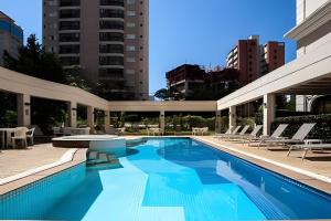 a swimming pool with chairs and a building at Apartamento Vila Olímpia. in Sao Paulo