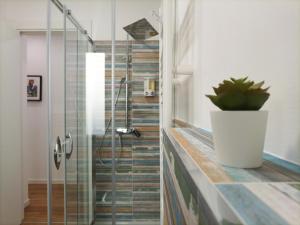una doccia in vetro in bagno con una pianta in vaso di Casa D'Antò a Petralia Sottana