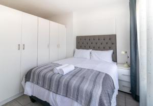 a bedroom with a bed with a gray and white blanket at Wavecrest 103 Holiday Apartment in Durban