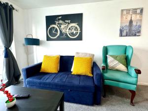 a living room with a blue couch and a green chair at Bright & Spacious Flat - Perfect for Exploring London , Slough & Windsor! in Slough
