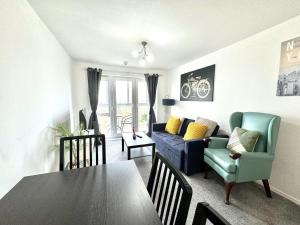 a living room with a table and a blue couch at Bright & Spacious Flat - Perfect for Exploring London , Slough & Windsor! in Slough