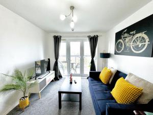 sala de estar con sofá azul y almohadas amarillas en Bright & Spacious Flat - Perfect for Exploring London , Slough & Windsor! en Slough