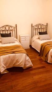 a bedroom with two beds and a wooden floor at Juancito Ángel in Río Cuarto