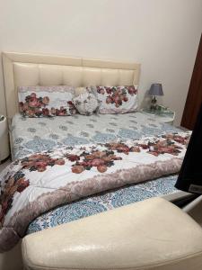 łóżko z kwiecistą kołdrą i poduszkami w obiekcie One BHK w mieście Adżman
