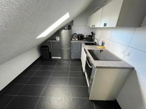 a kitchen with white cabinets and a tile floor at Moderne gemütliche 2-Zimmer Wohnung Stuttgart Bad-Cannstatt in Stuttgart