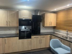 a kitchen with wooden cabinets and black appliances at Room in Essex in Pitsea