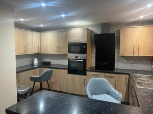 a kitchen with black appliances and wooden cabinets at Room in Essex in Pitsea