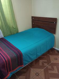 a bed in a room with a blue sheet on it at Cabañas doña carmen in Punta de Choros