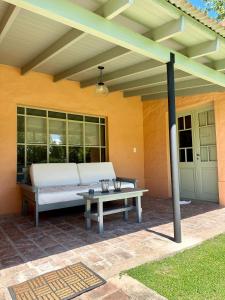 een patio met een witte bank en een tafel bij Los Narcisos in San Antonio de Areco