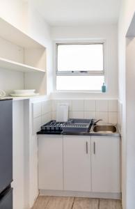 cocina blanca con fregadero y ventana en Wavecrest 1205 Holiday Apartment, en Durban
