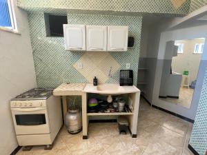 une petite cuisine avec un évier et une cuisinière dans l'établissement Apartamento a 1 km da Orla de Atalaia 2º andar, à Aracaju
