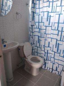 y baño con aseo, lavamanos y cortina de ducha. en cabañas de la casona, en Punta de Choros