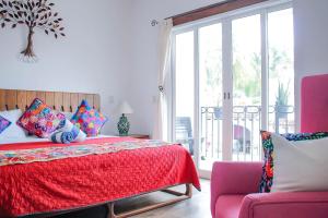 Un dormitorio con una cama con una colcha roja y una silla en Refugio del Mar Luxury Hotel Boutique, en Bucerías