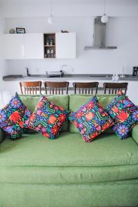 a green couch with four colorful pillows on it at Refugio del Mar Luxury Hotel Boutique in Bucerías