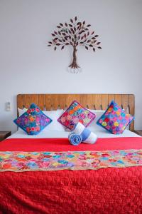 una cama roja con almohadas y un árbol en la pared en Refugio del Mar Luxury Hotel Boutique en Bucerías