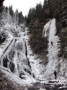 una persona parada frente a una cascada en Pensiunea K9, en Răchiţele